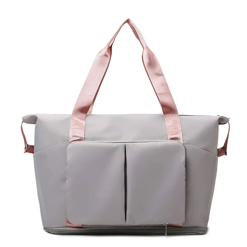 Gray travel duffel bag with front organizer pocket, top handles, and side carry straps.