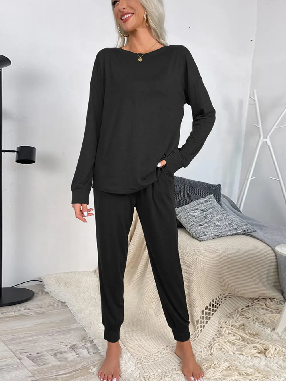 Black long-sleeve round-neck lounge top and drawstring jogger pants, side view