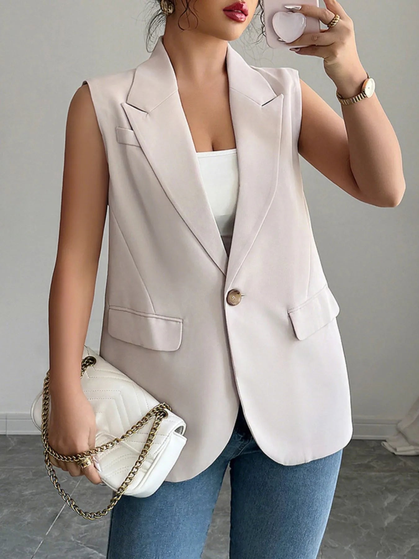 Eggshell sleeveless blazer with one button, notched lapels, and flap pockets