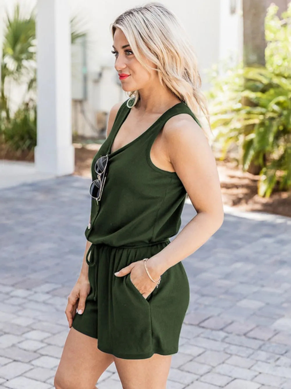 Dark green scoop-neck romper with wide straps, button detail, and drawstring waist