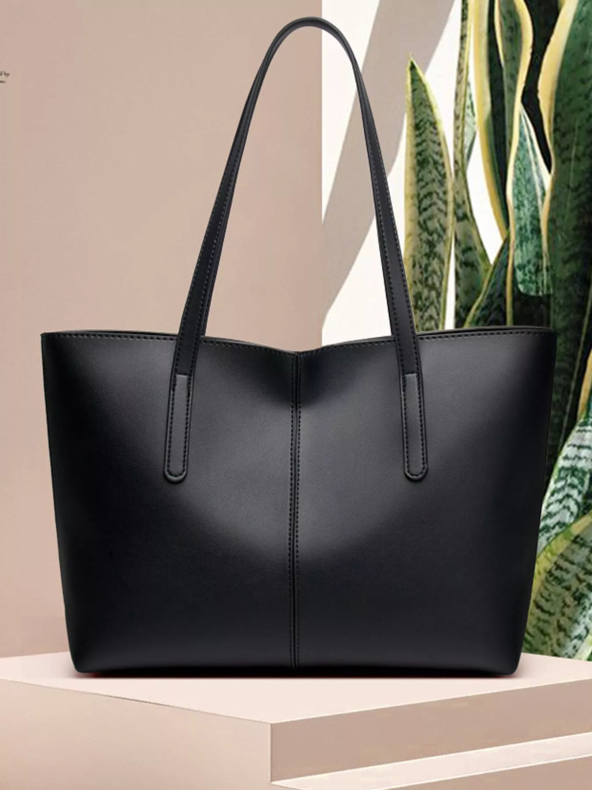 Black medium vegan leather tote bag with upright handles and smooth front panel