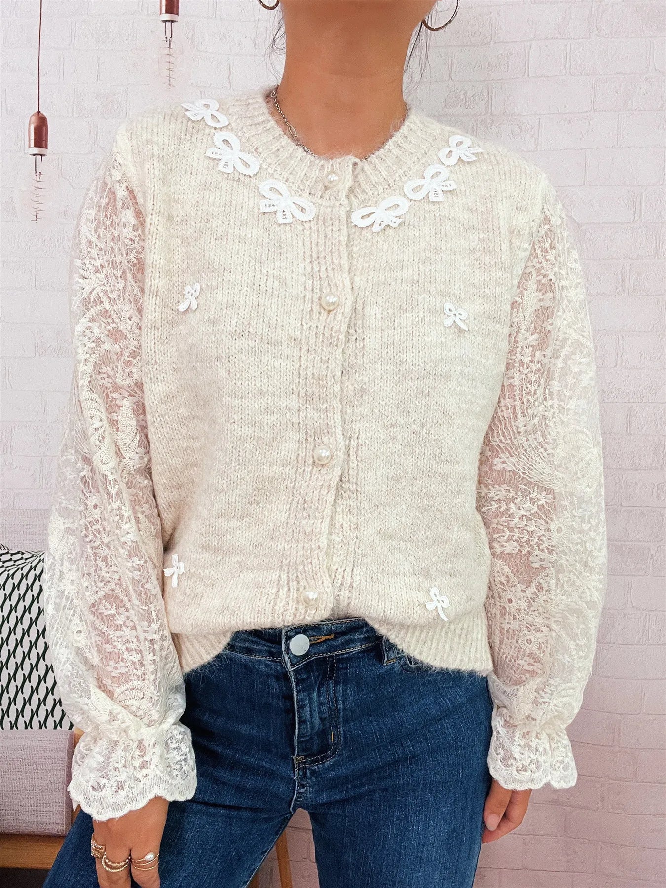 Cream knit button-up cardigan with lace puff sleeves and embroidered bow-like trim