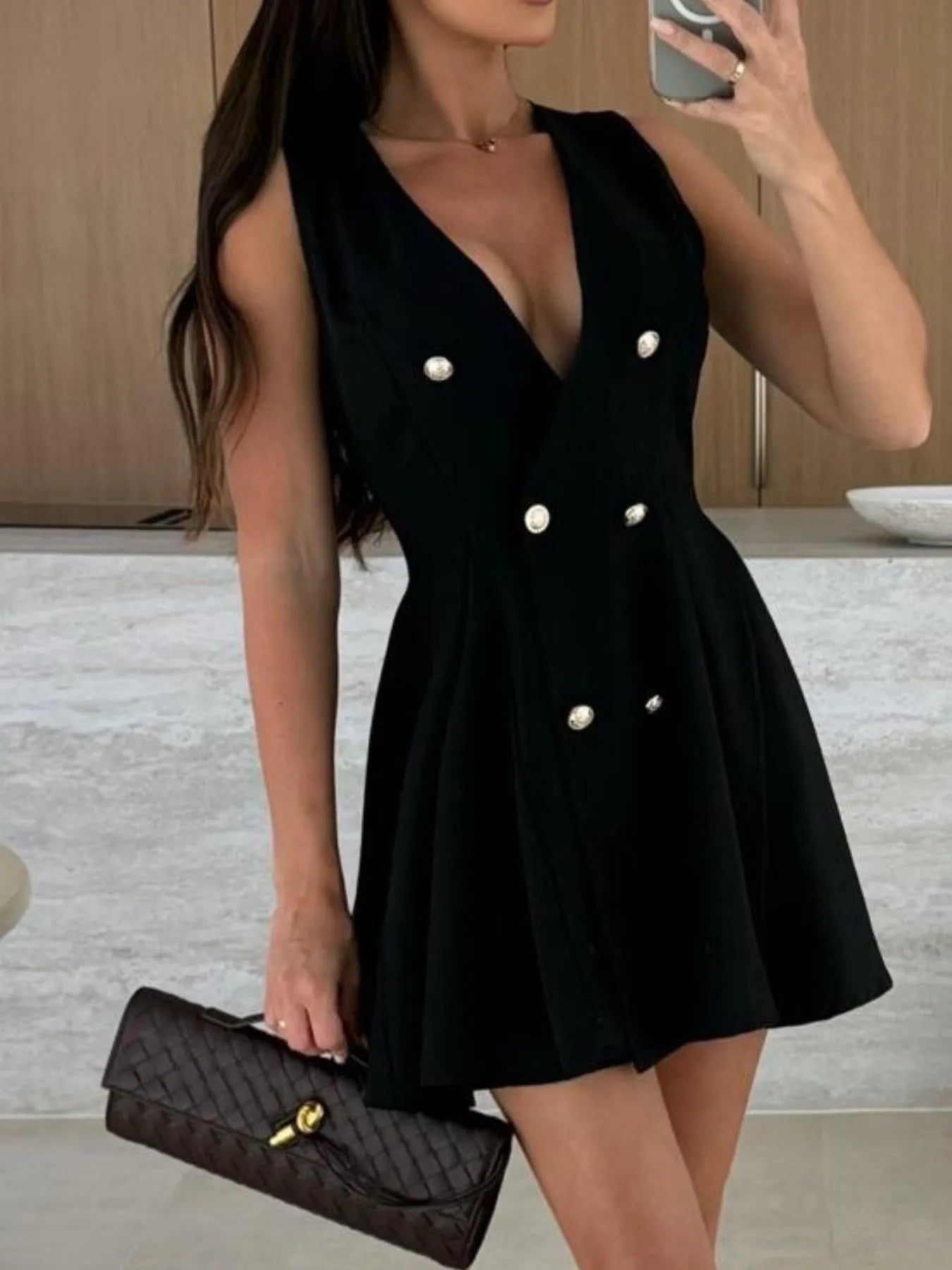 Sleeveless double-breasted black mini dress with gold buttons and pleated detailing