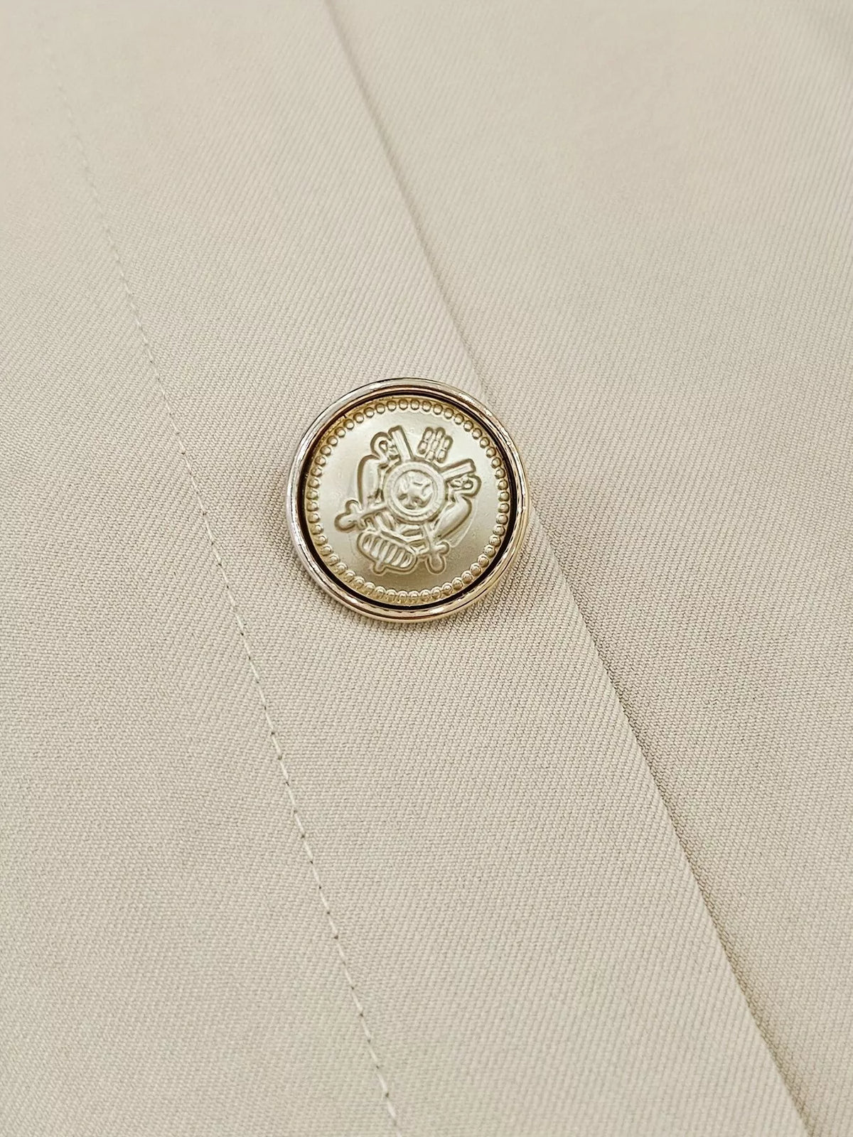Gold-toned decorative button on apricot skirt front