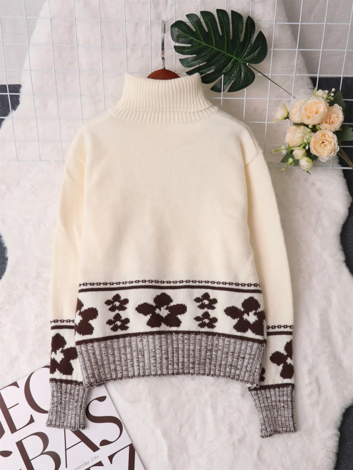 Cream sweater back view with ribbed turtleneck and black flower intarsia stripe at hem