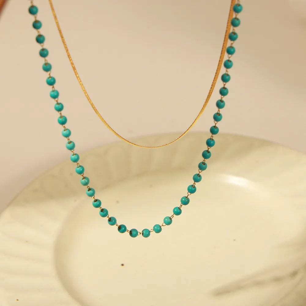 Double-layer necklace with turquoise bead strand and gold curved chain, front view