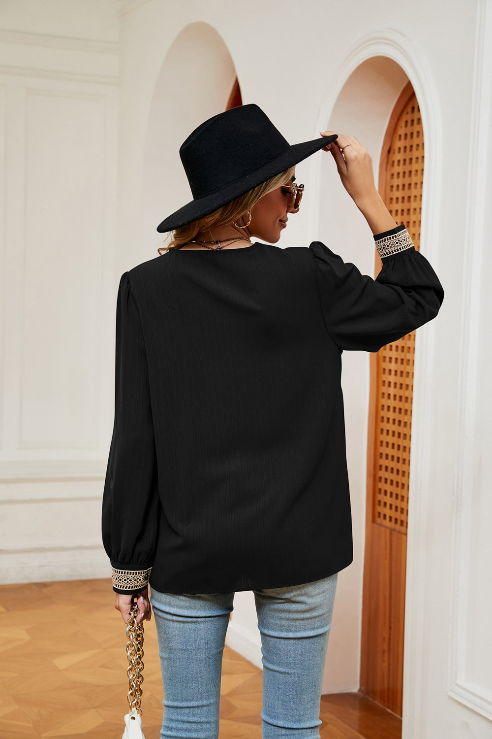 Black blouse with contrast trim at cuffs and long puff sleeves, back view