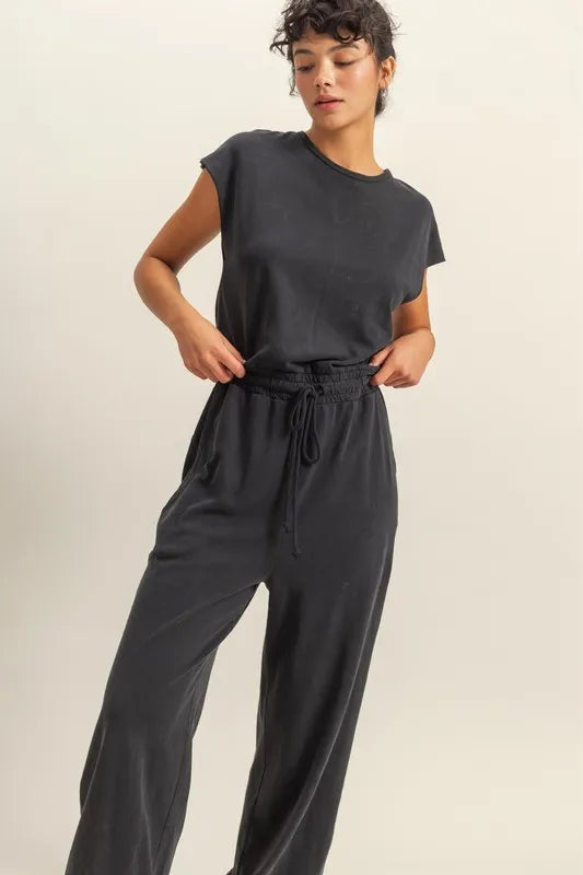 Black cap-sleeve jumpsuit with round neckline and drawstring waist, full-length pants.