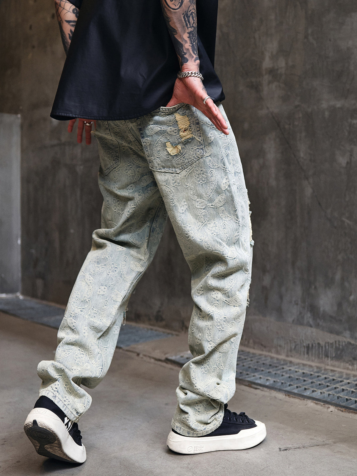 Light wash wide-leg distressed jeans with button fly, worn patches, and roomy leg