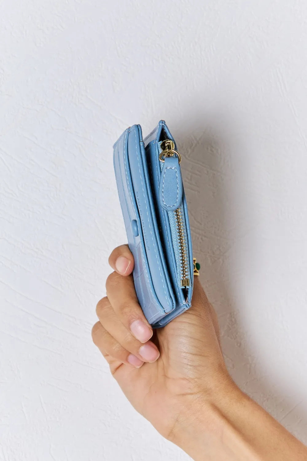 Blue textured vegan leather mini wallet side view with gold zipper hardware.