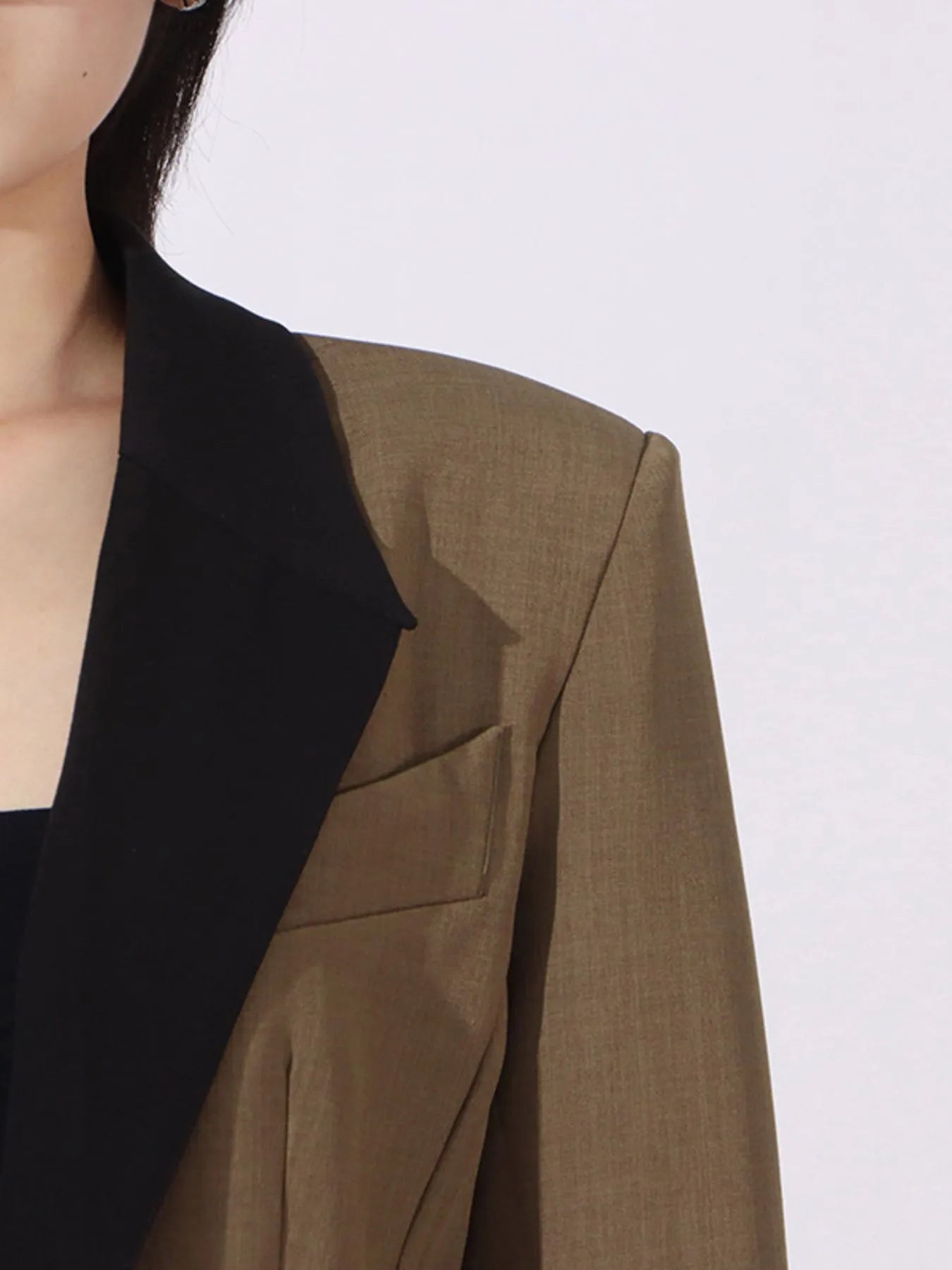 Black contrast lapel detail on a khaki green blazer with flap pocket opening