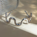 Wave-shaped stainless steel bracelet with wavy open cuff, silver tone finish.
