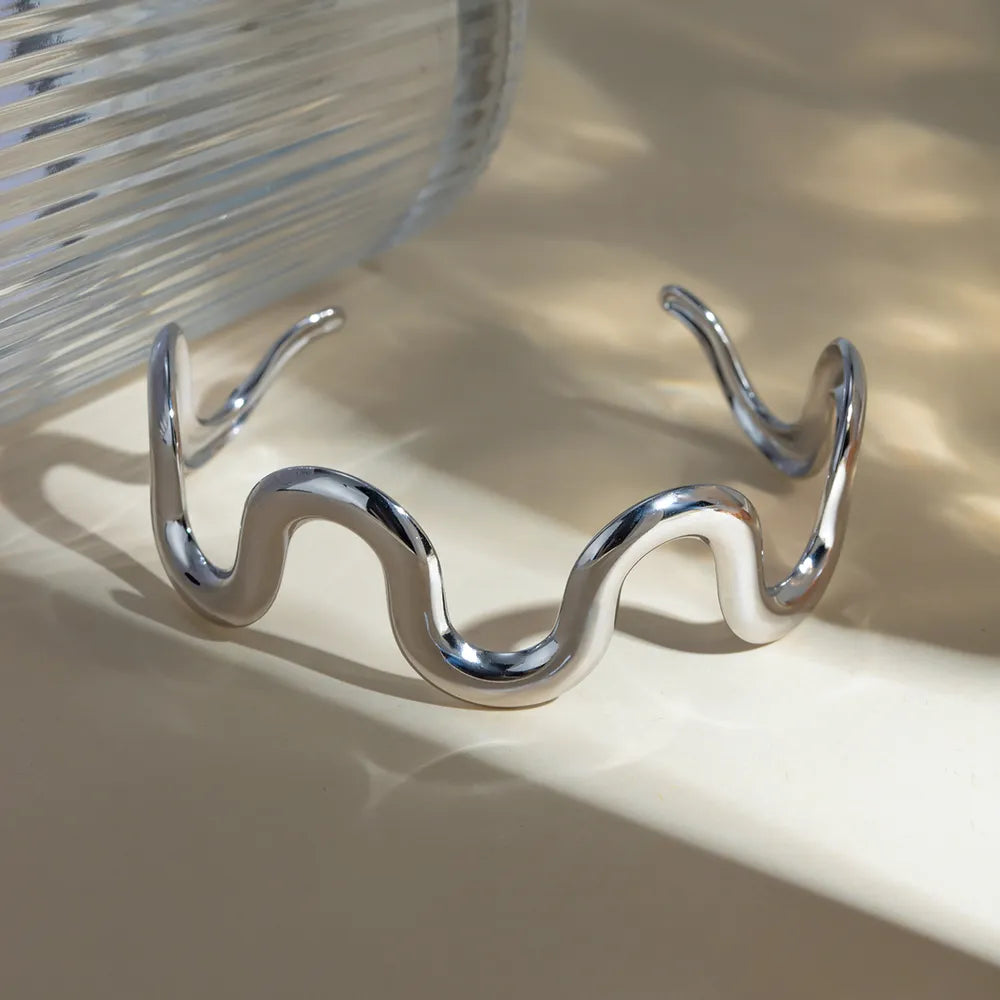 Wave-shaped stainless steel bracelet with wavy open cuff, silver tone finish.
