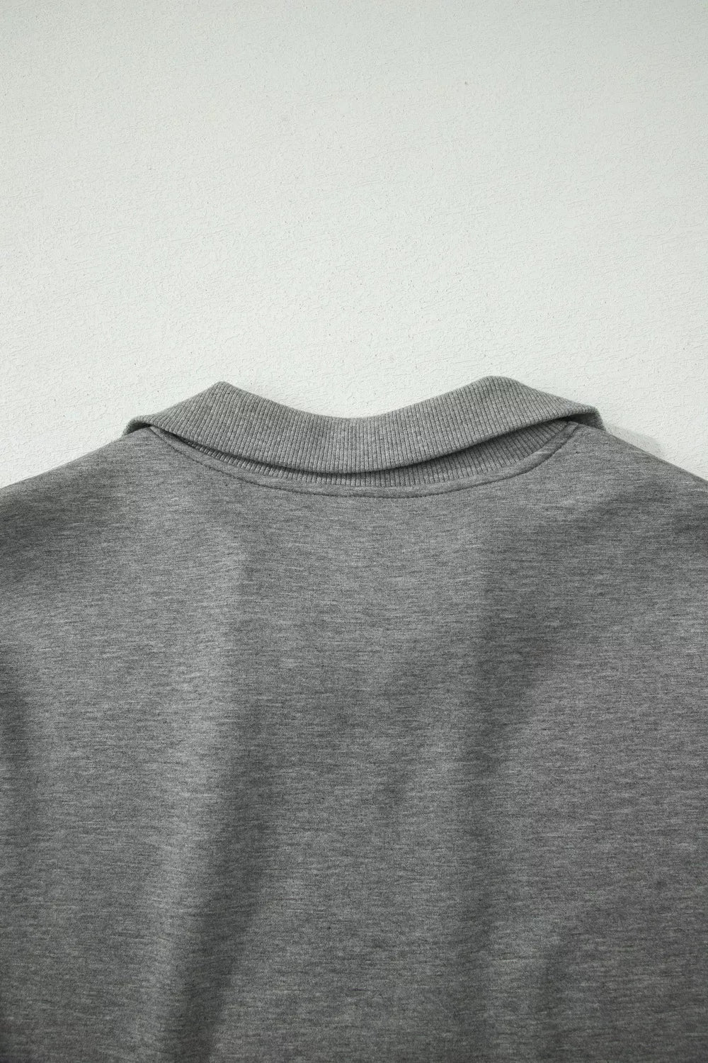Dark gray polo top back with ribbed collar and smooth knit fabric.