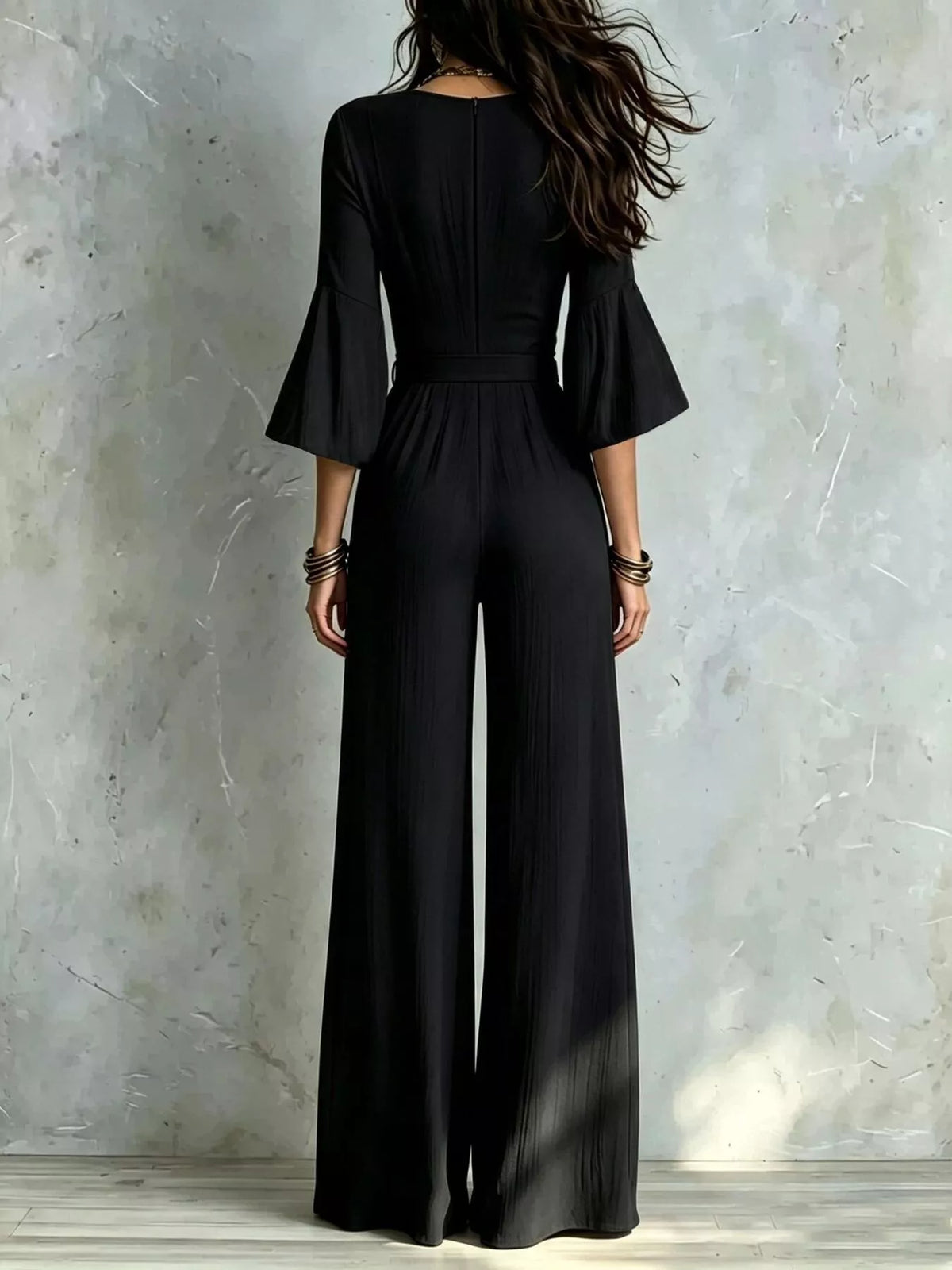 Black wide-leg jumpsuit with V-neck, pleated wrap bodice, and tie waist