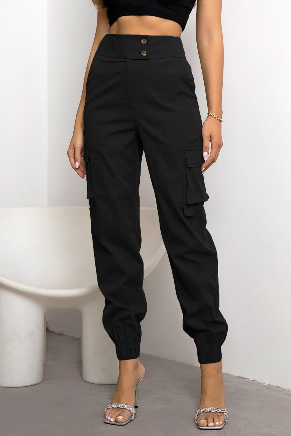 High-waist cargo pants, black with front button closure and side cargo pocket, ankle cuffs
