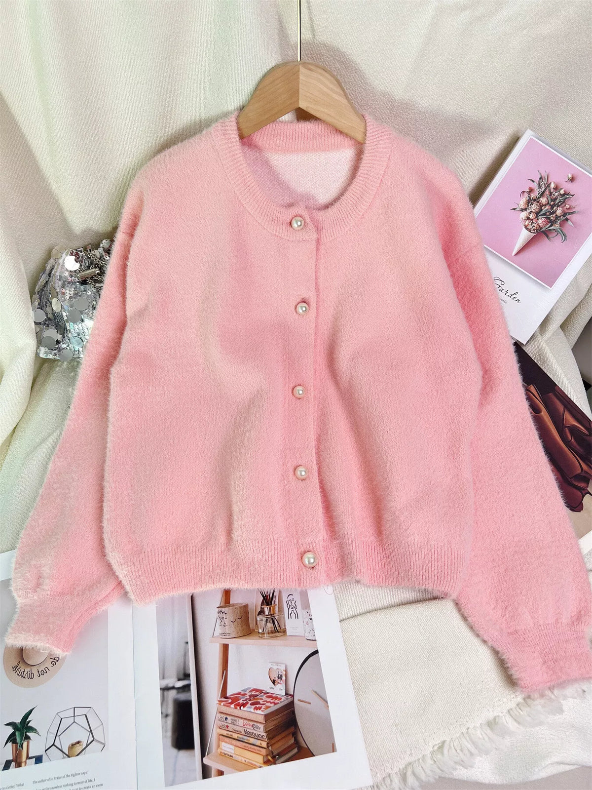 Pink fuzzy knit button-front cardigan sweater with long sleeves and pearl buttons