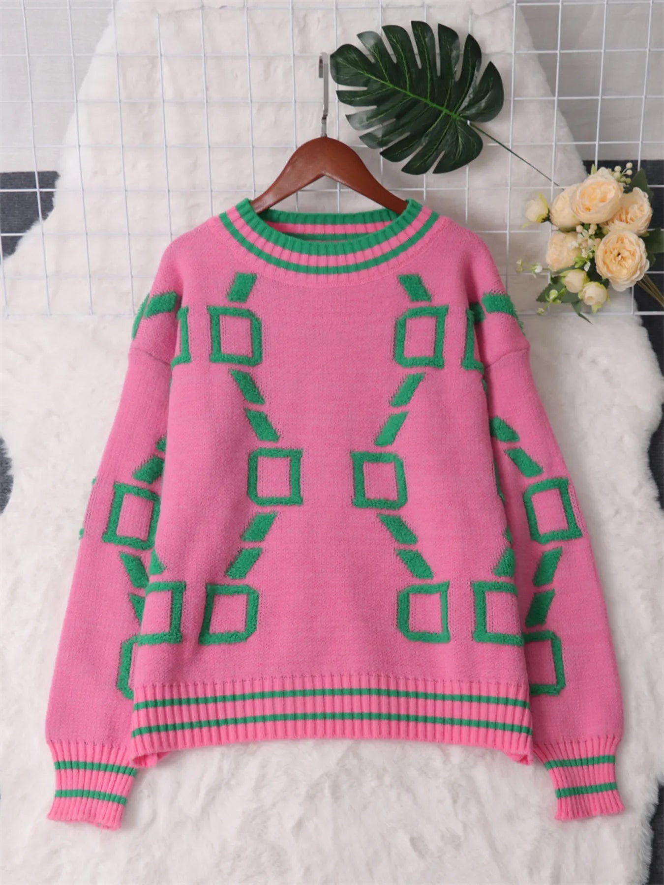 Pink knit sweater with green square graphic pattern and ribbed round neckline