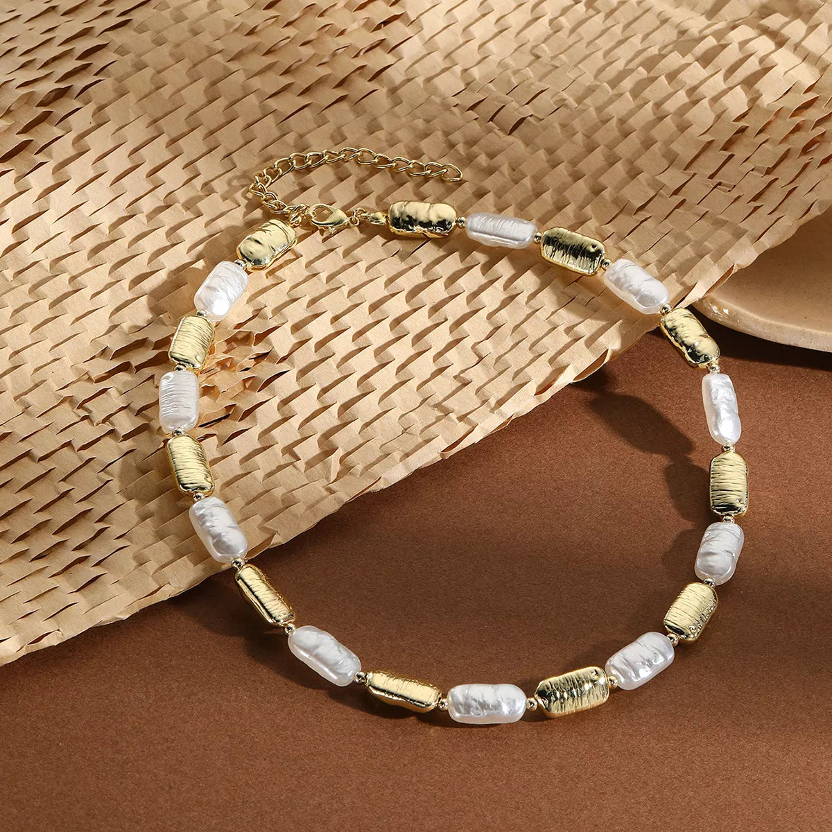 Pearl chain necklace with gold-tone accents and white baroque pearl beads, flat lay