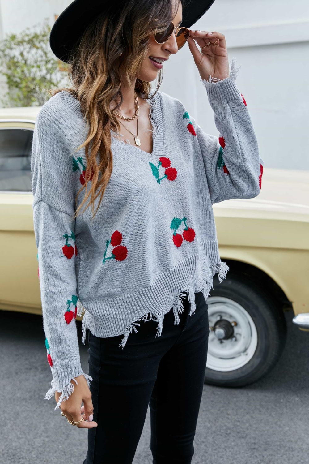 Sky blue cherry-pattern V-neck sweater with frayed hem and cuff tassel details