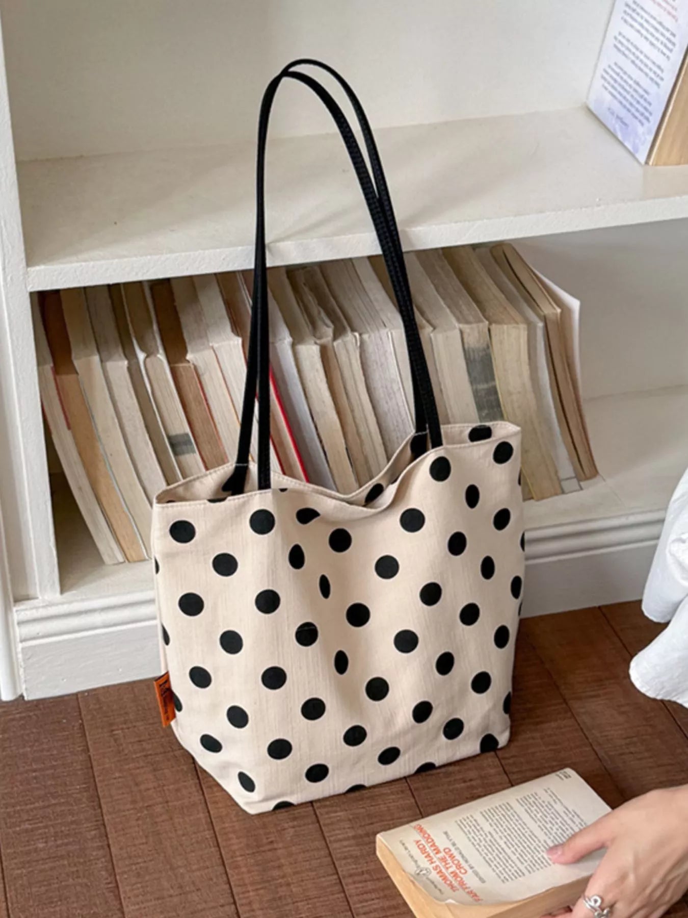 Cream polka dot shoulder bag with black dots, upright tote shape, and long handles