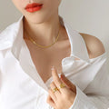 Gold-plated necklace with slim chain, worn at neckline