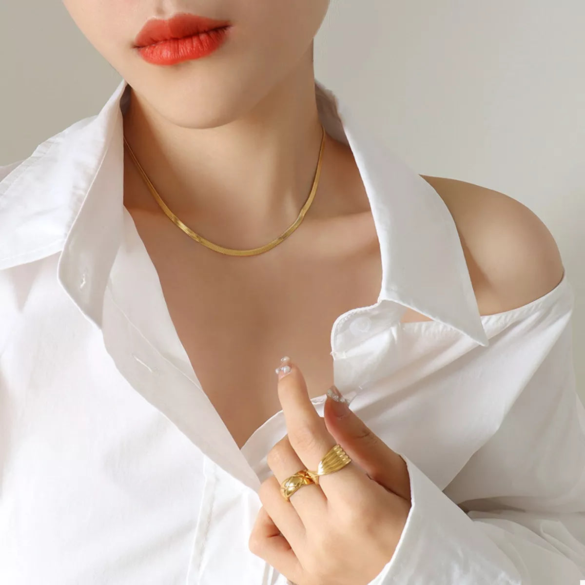 Gold-plated necklace with slim chain, worn at neckline
