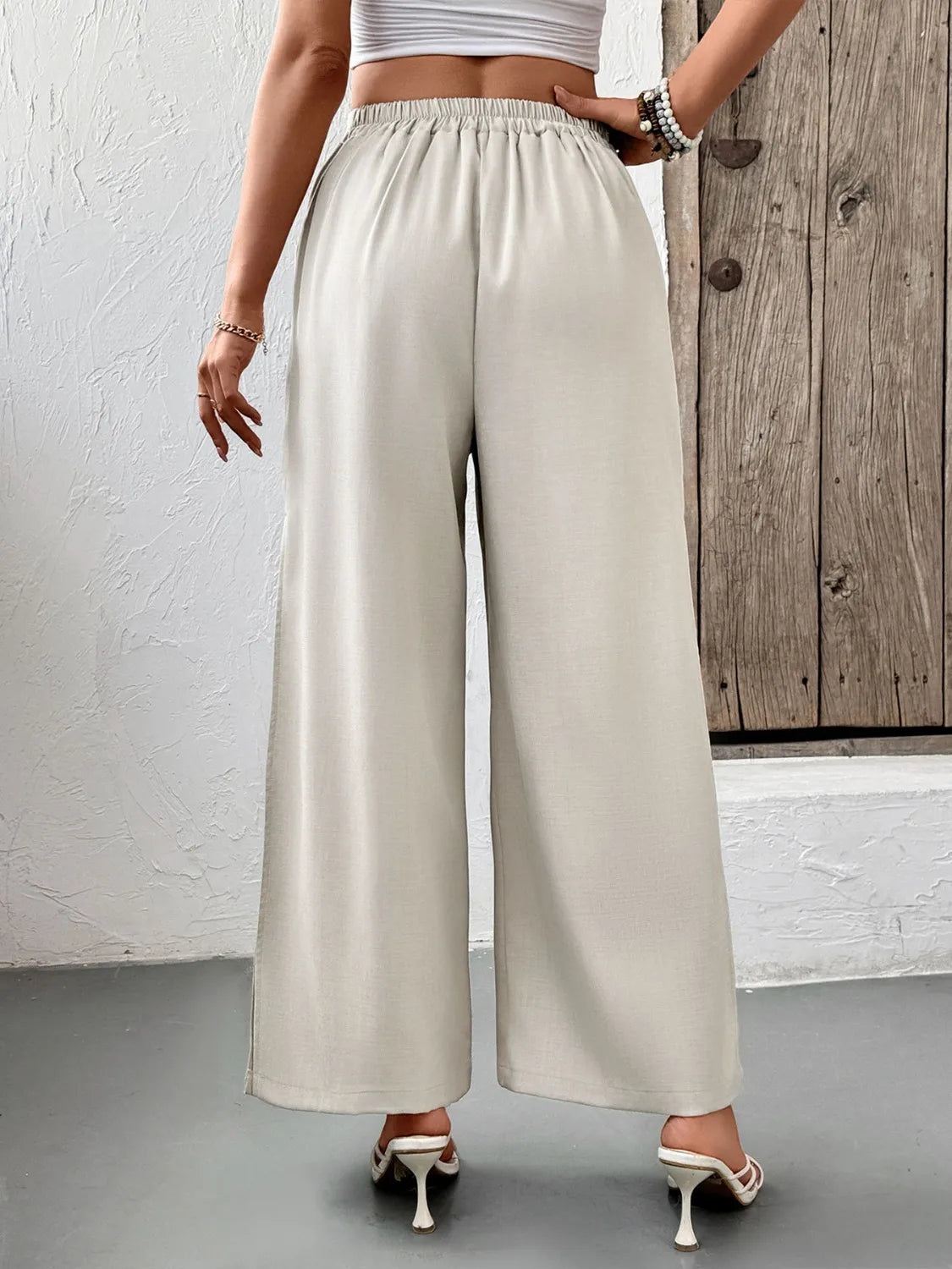 Beige wide-leg pleated pants with elastic waistband and side slits