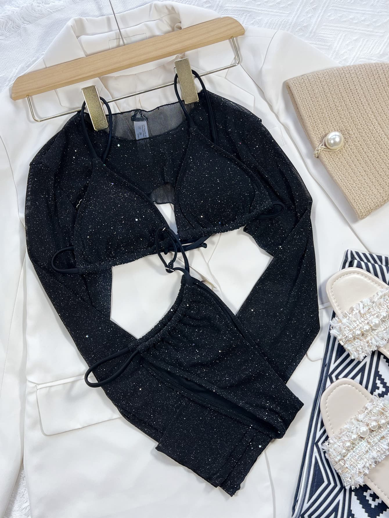Black glitter three-piece swim set laid out: long-sleeve crop top, triangle bikini top, and bottoms