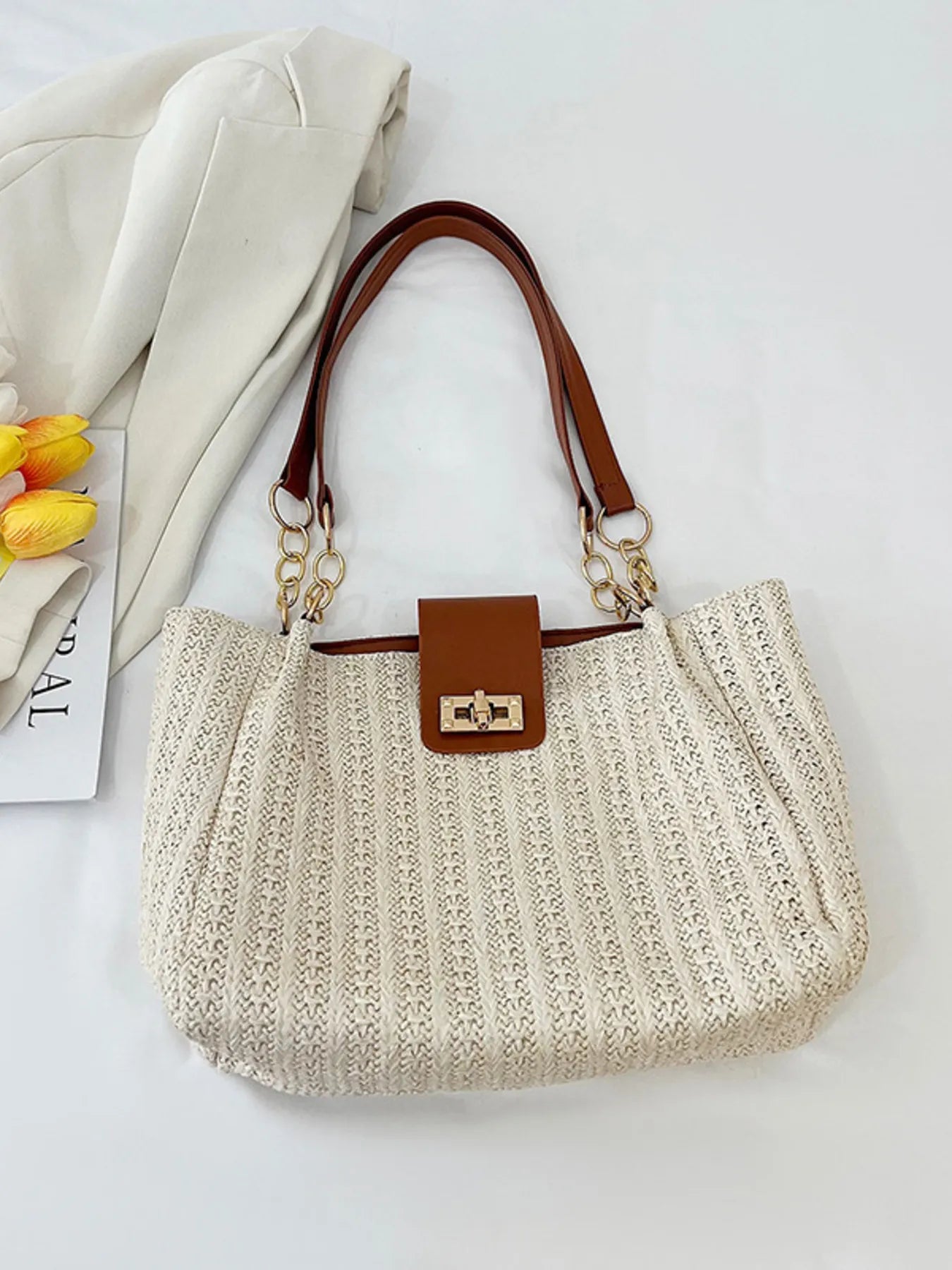 Woven straw shoulder bag with brown handle straps and gold-tone chain, beige woven front