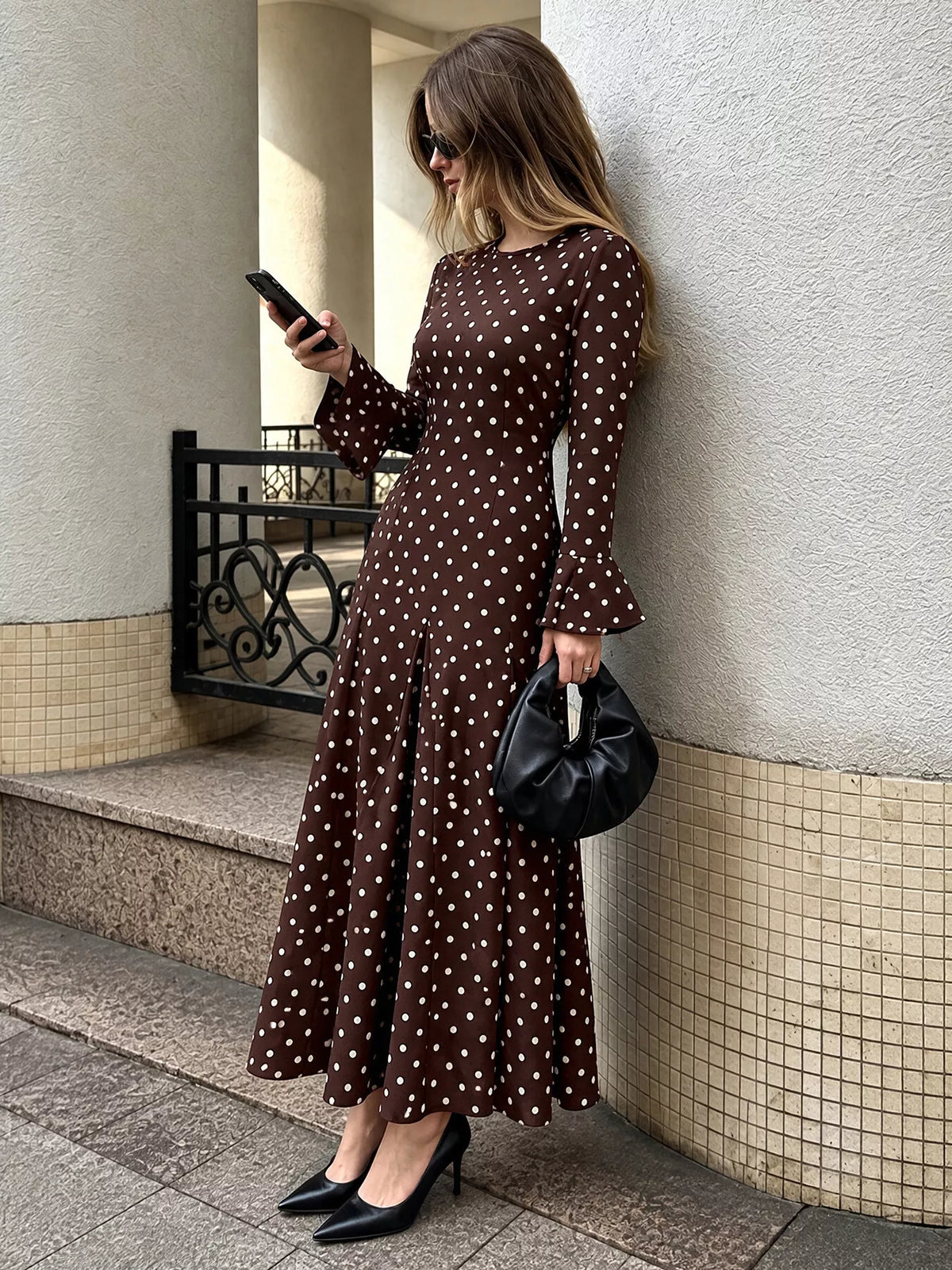 Coffee brown polka dot long-sleeve maxi dress, side view with flared hem