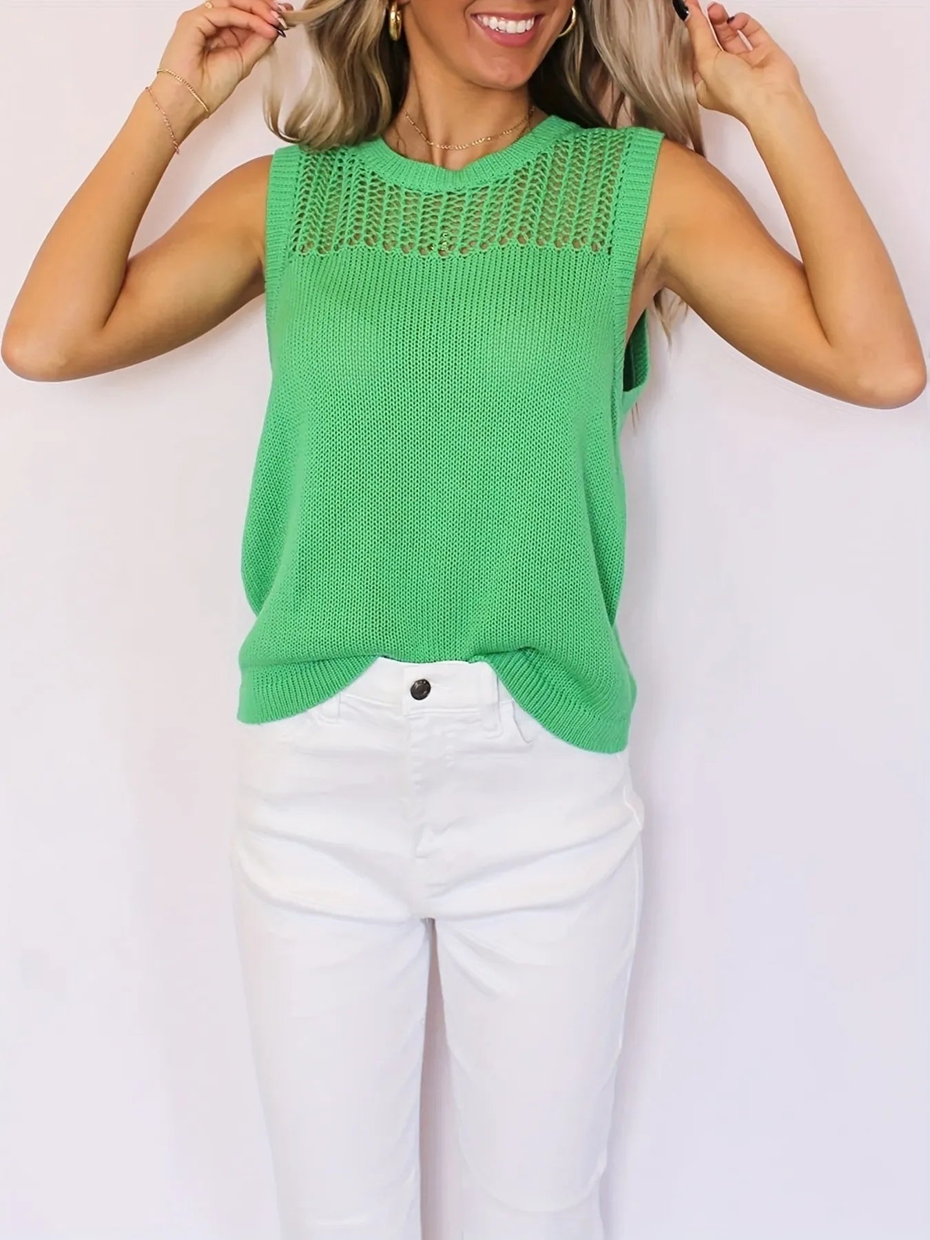 Green sleeveless openwork round neck sweater vest paired with white jeans