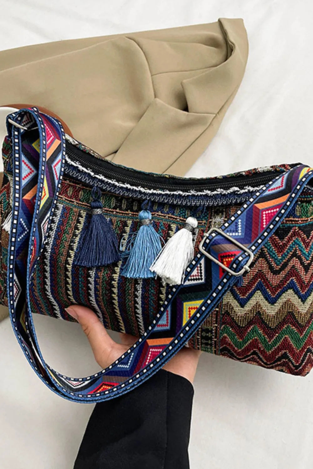 Tassel shoulder bag with adjustable strap, navy zigzag pattern and multiple tassel decorations.