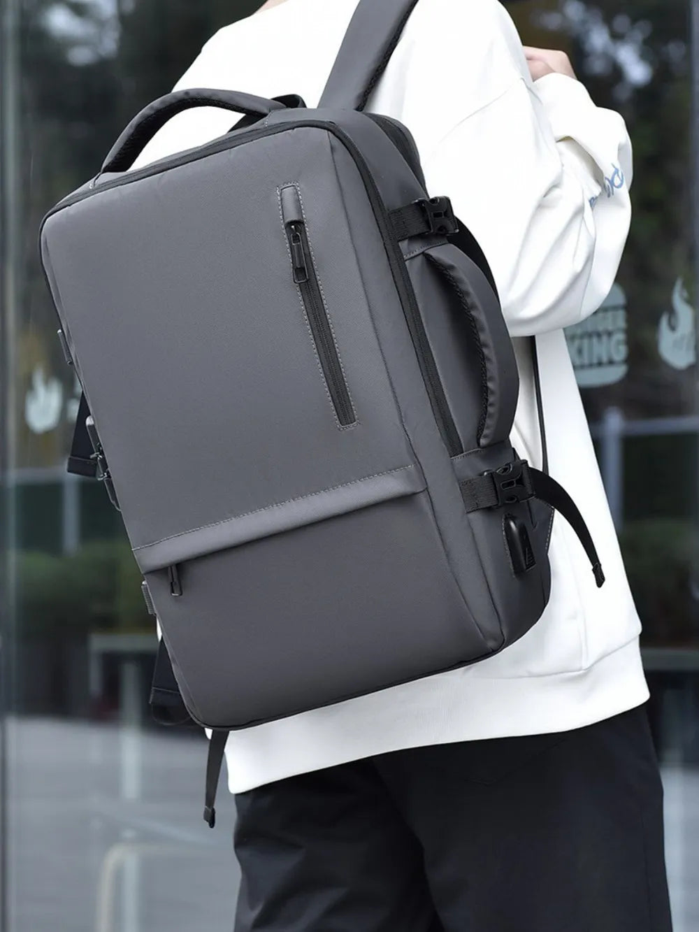 Dark gray backpack worn over a shoulder with front zip pocket and straps