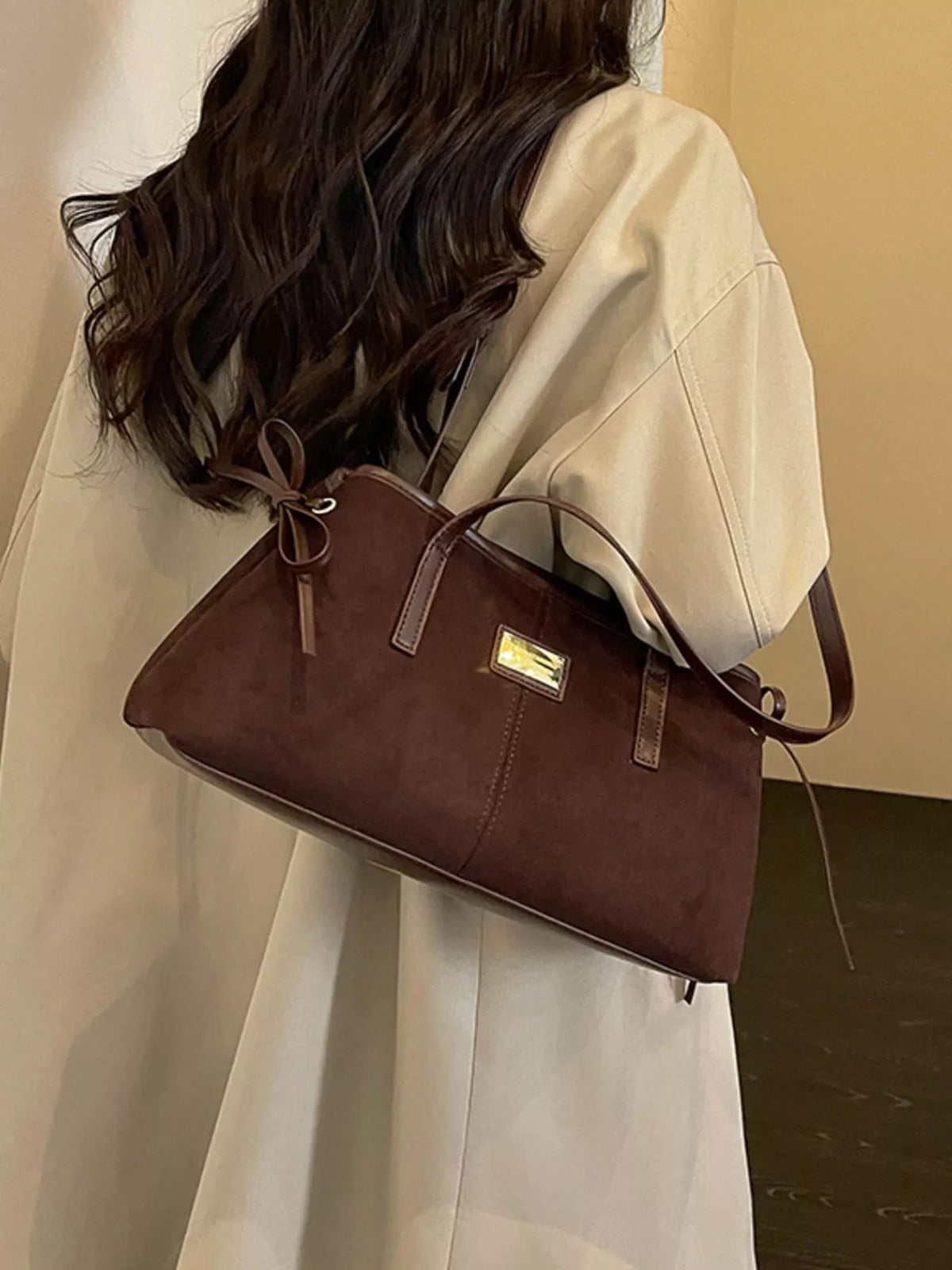 Medium suede side-tie shoulder bag in brown, worn on shoulder with side tie straps
