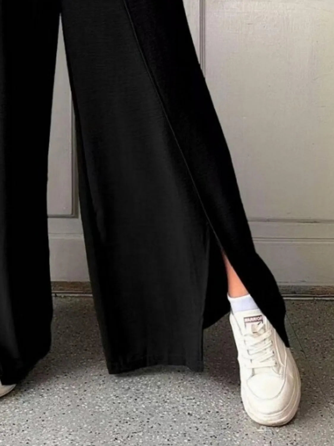 Black wide-leg pants with long side slit and smooth flowing fabric