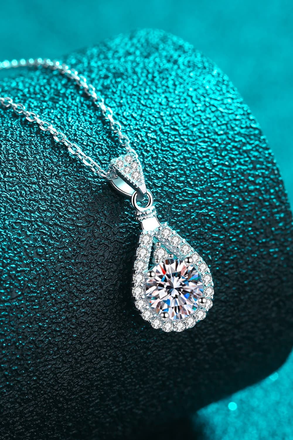 Sterling silver moissanite teardrop pendant with halo surround, side view on chain