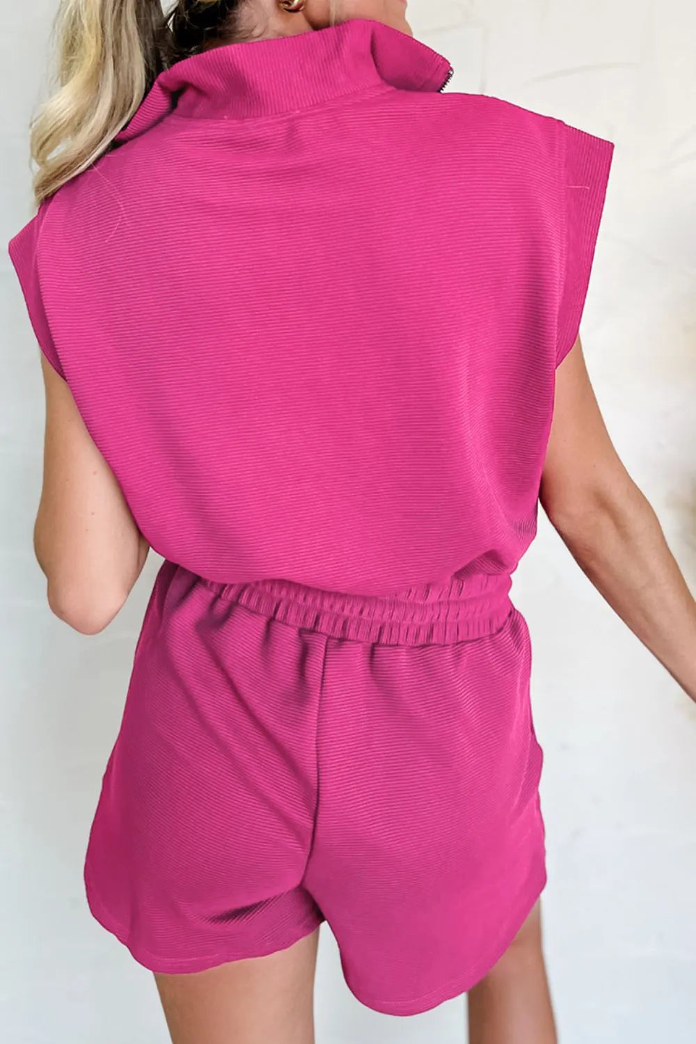 Hot pink textured romper back view with short sleeves and elastic waist with rouching