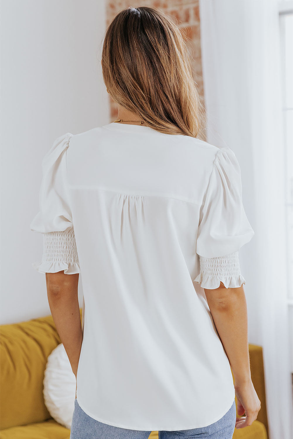 White blouse back view with puff sleeves and gathered yoke, smocked cuff details
