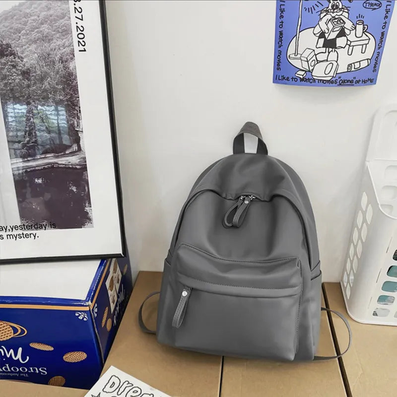 Dark gray vegan leather zip backpack with drawstring front pocket and top handle