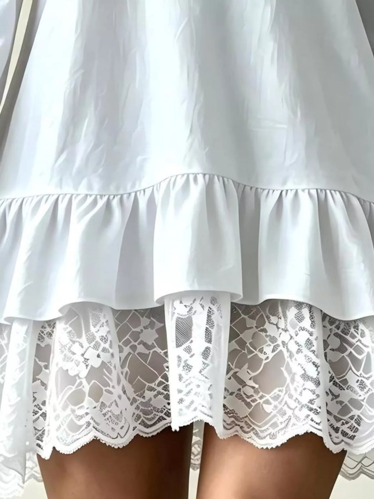 White flounce dress with tiered ruffle hem and lace panel detail at hemline