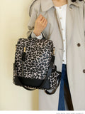 Leopard print backpack with black trim, front zip pocket, and adjustable shoulder straps.