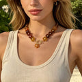 Gold beaded necklace with dark red-brown resin flowers and small gold link clasp
