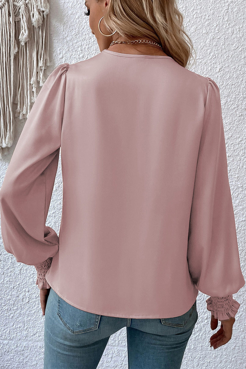 Light mauve surplice-neck lantern sleeve blouse from the back with gathered cuffs.