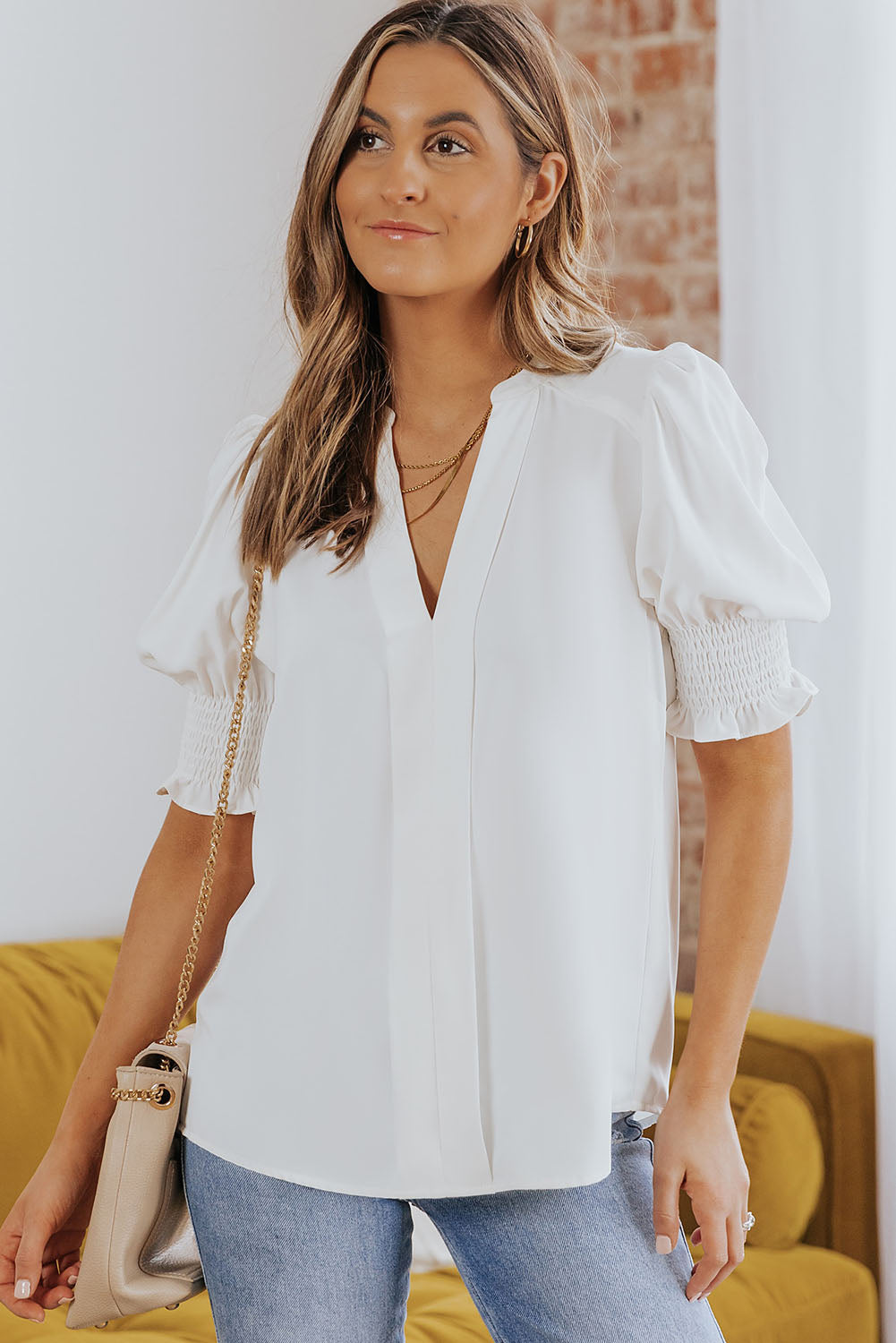 White smocked flounce sleeve blouse with notched V-neck and gathered puff sleeves