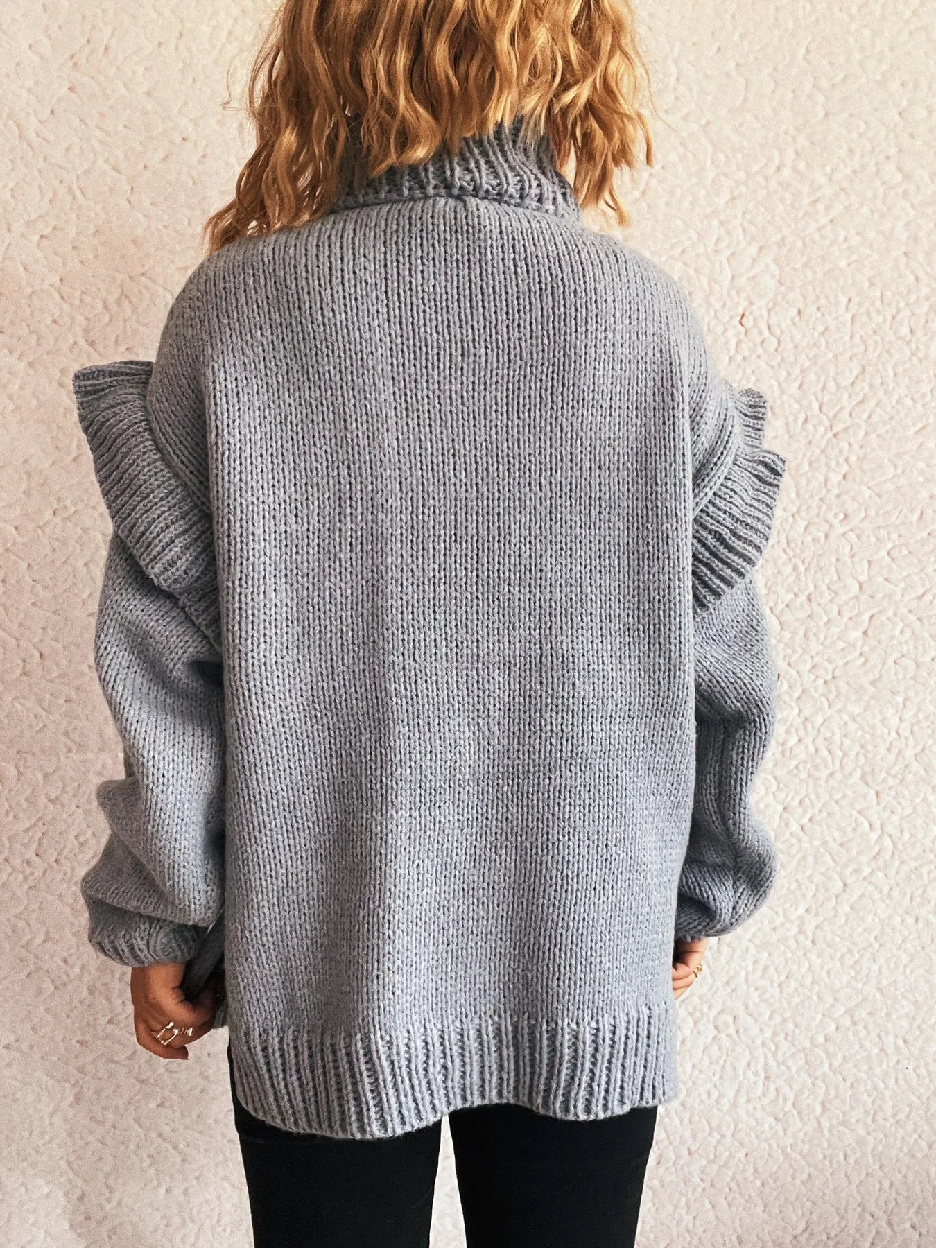 Grey ruffled turtleneck long-sleeve knit sweater, back view with ribbed hem