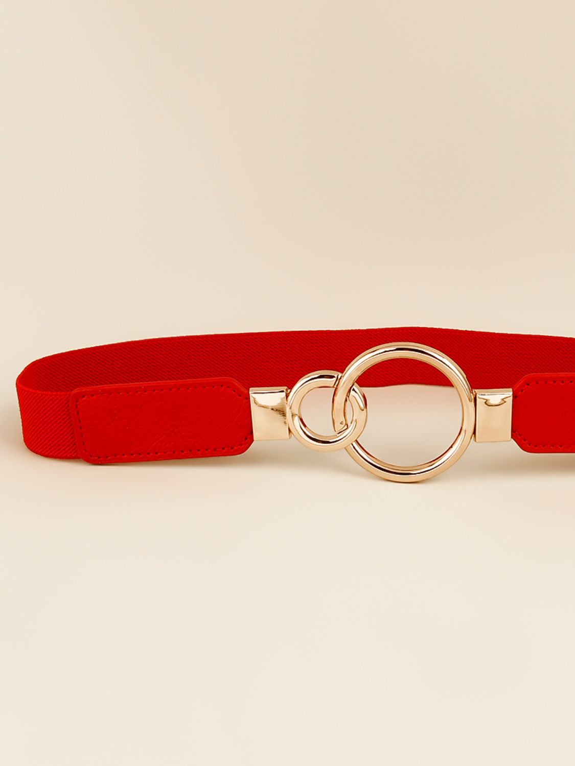 Red elastic belt with double ring buckle, rose-gold metal, and adjustable strap ends