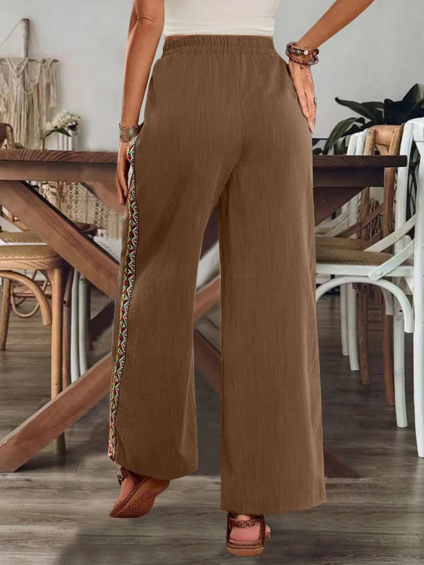 Brown wide-leg pants with elastic waistband and embroidered side stripe, straight fall.