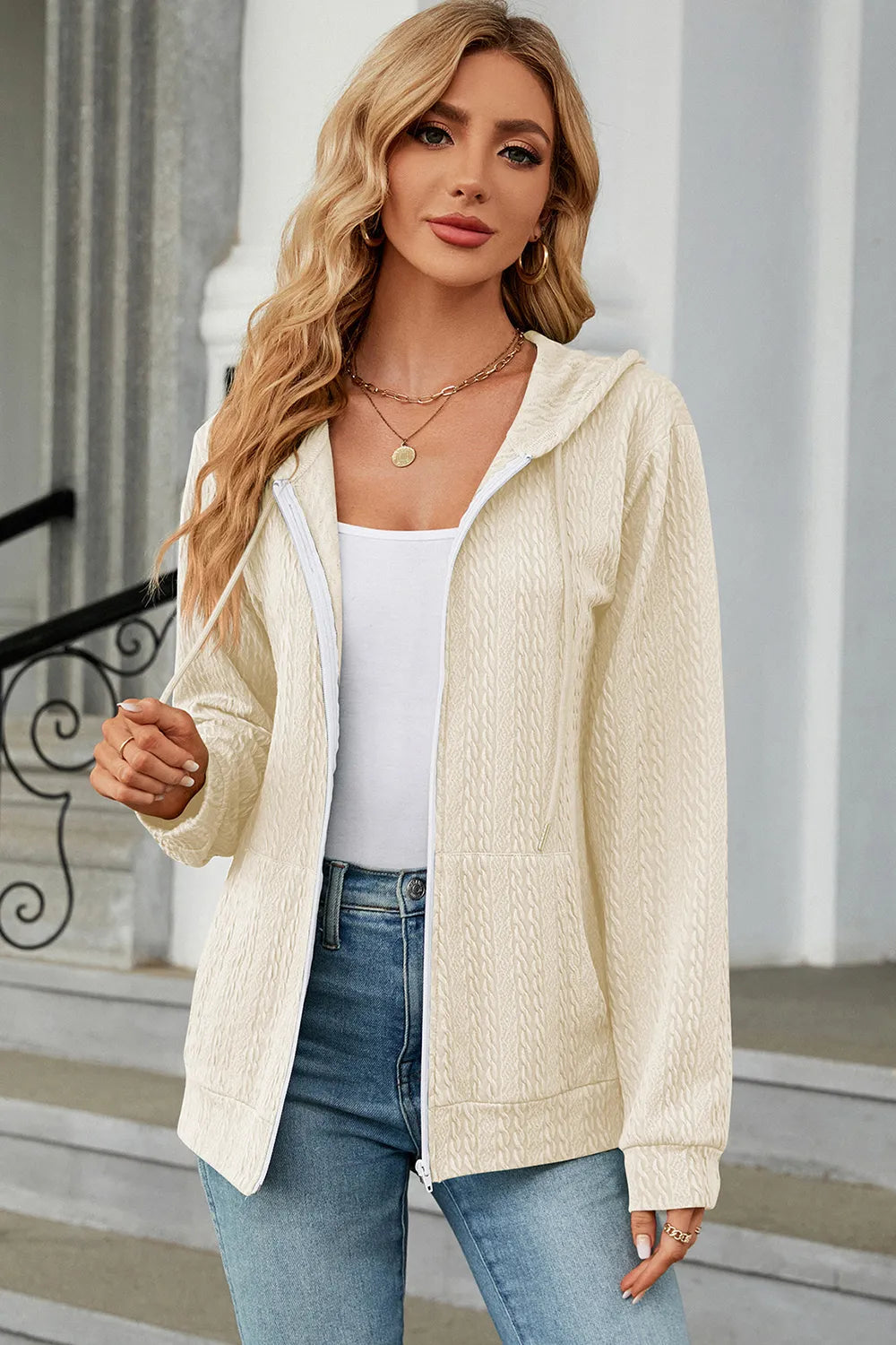Cream zip-up hoodie with hood and long sleeves, textured fabric and front zipper