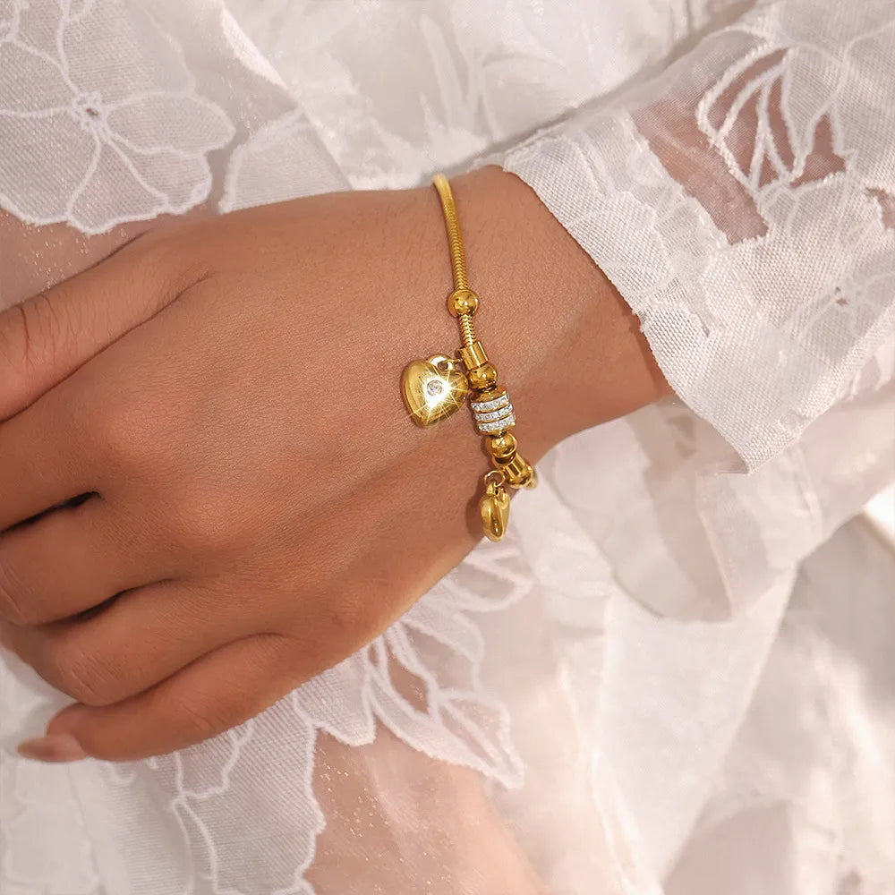 Gold-plated heart charm bracelet with small heart charms and rhinestone bead detail